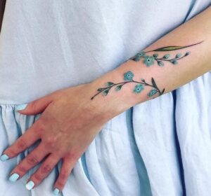 tatuaggio braccio fiori blu avvolgenti